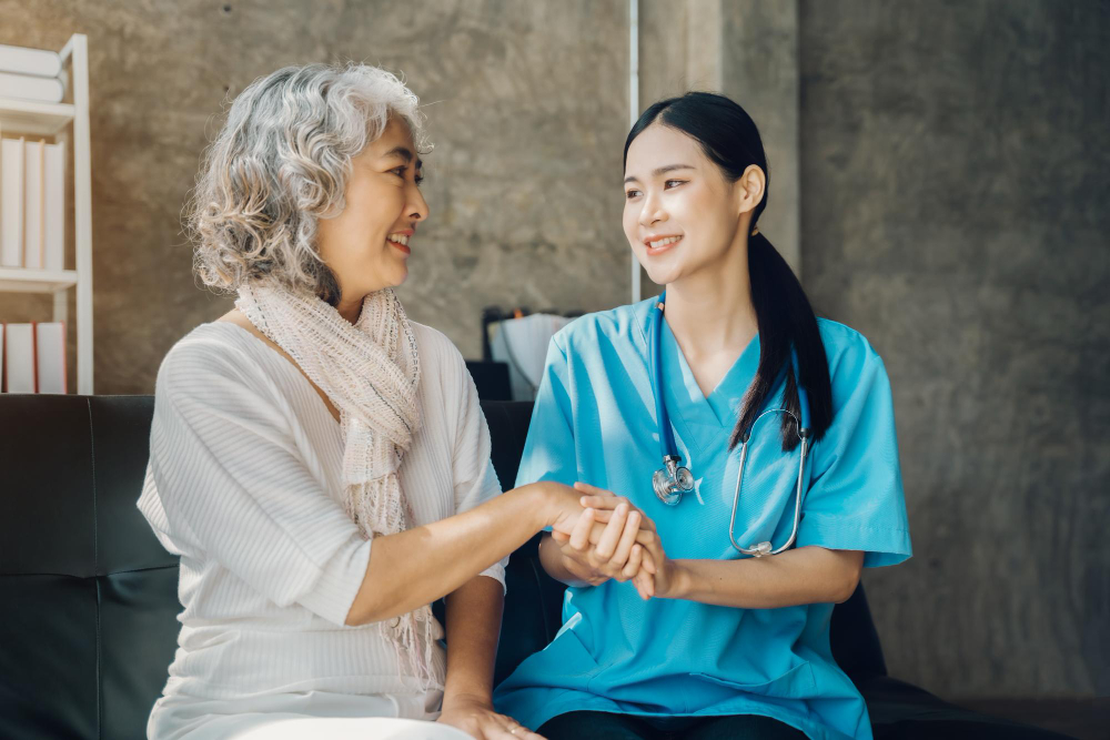 Smiling senior and caregiver talking together during a home visit, representing how to hire a home health aide in Brooklyn.